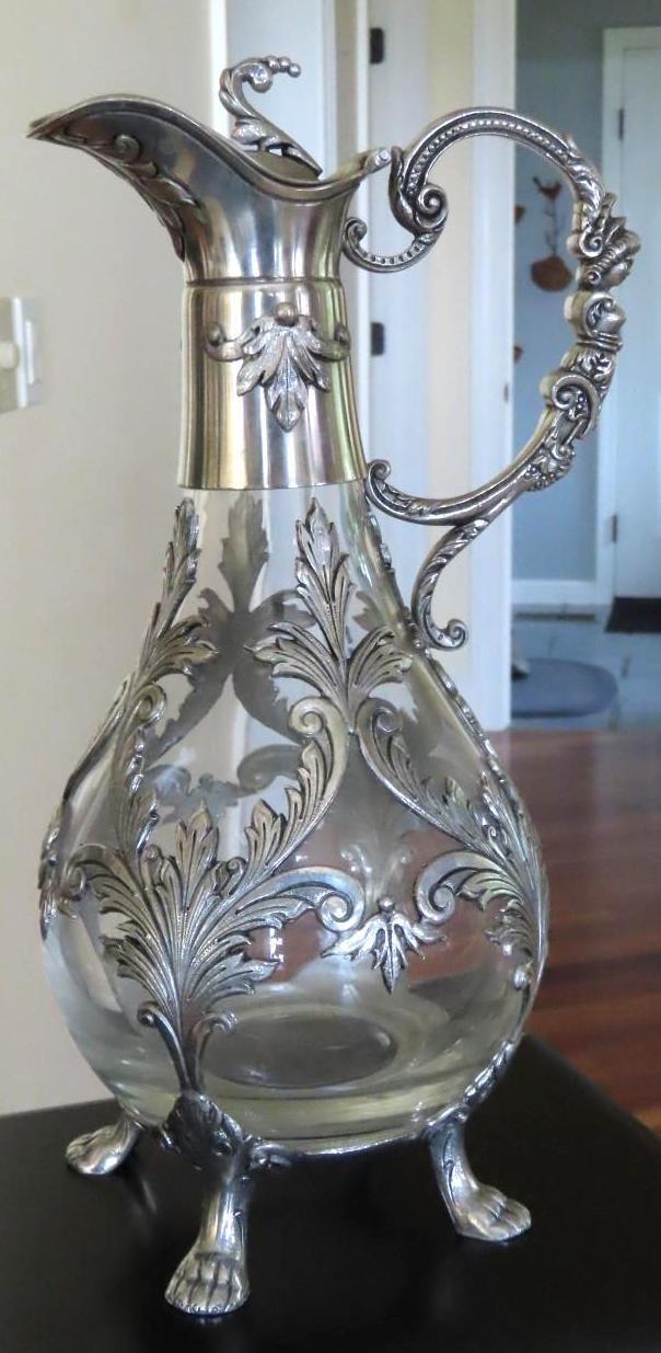 Silver pitcher with intricate floral details and decorative handle.