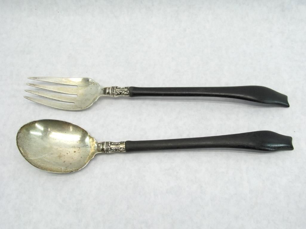 Silver fork and spoon with black handles, lying on a white surface.