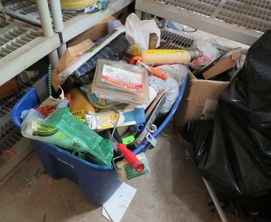 Blue wheelbarrow overflowing with tools, paint rollers, and other supplies.