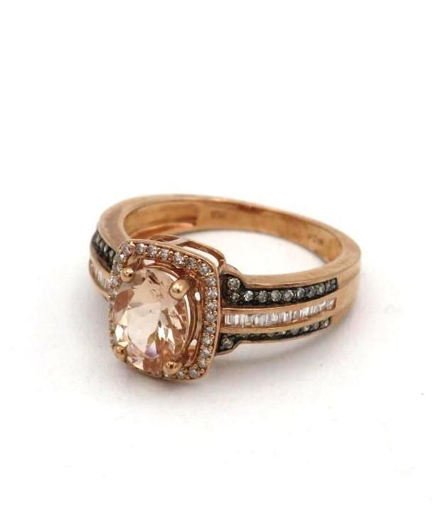Rose gold ring with a peach-colored center stone, halo, and accent diamonds; white background.