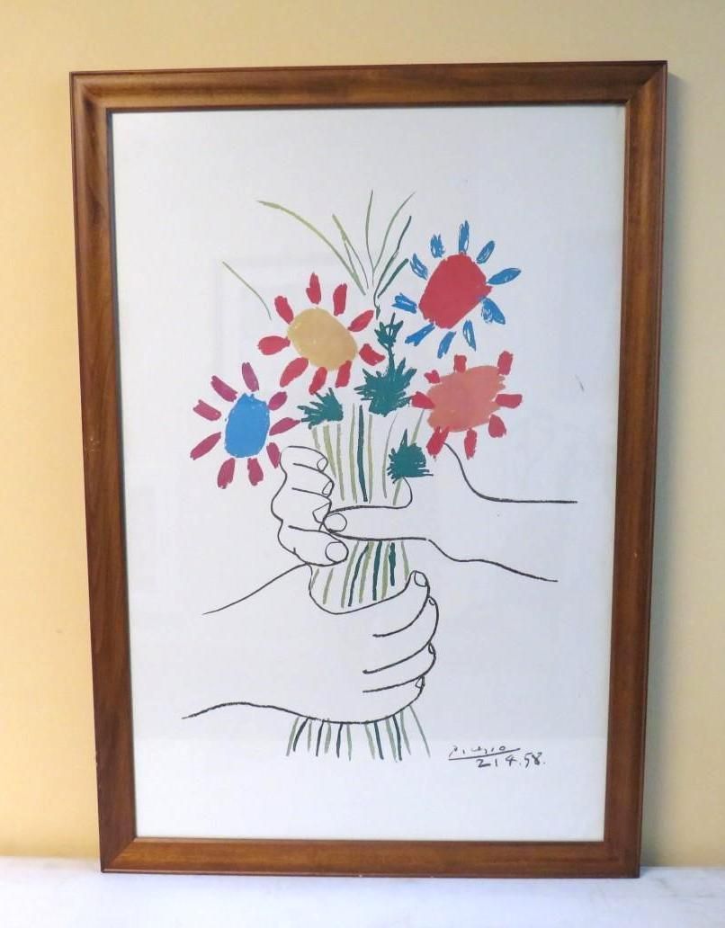 Hands holding a bouquet of colorful flowers in a wooden frame.