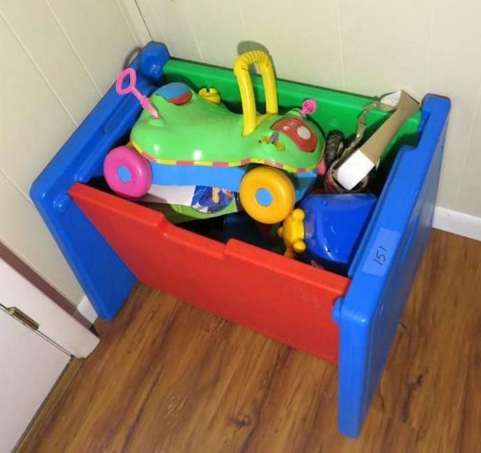 Blue, red, and green toy bin filled with toys on a wood floor.