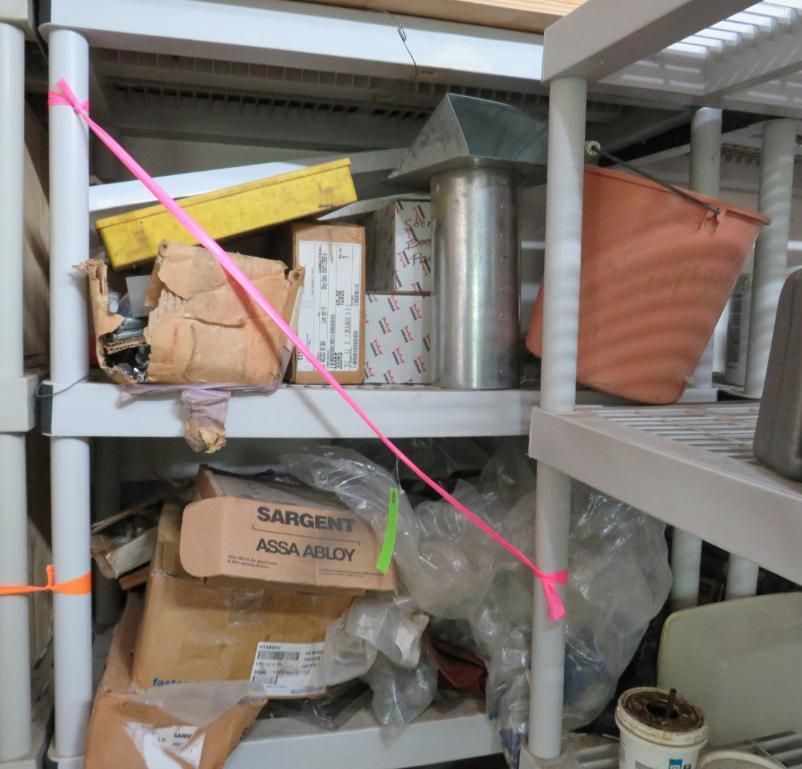 Shelving unit with items, pink ribbon securing a shelf, yellow and brown boxes.
