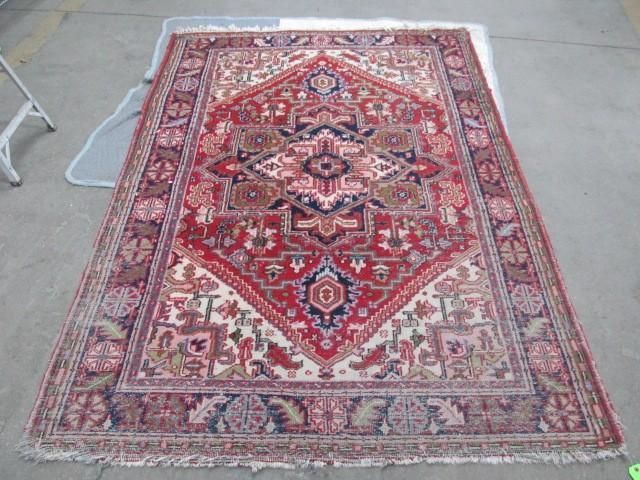 Red and cream patterned Oriental rug on a light-colored surface.