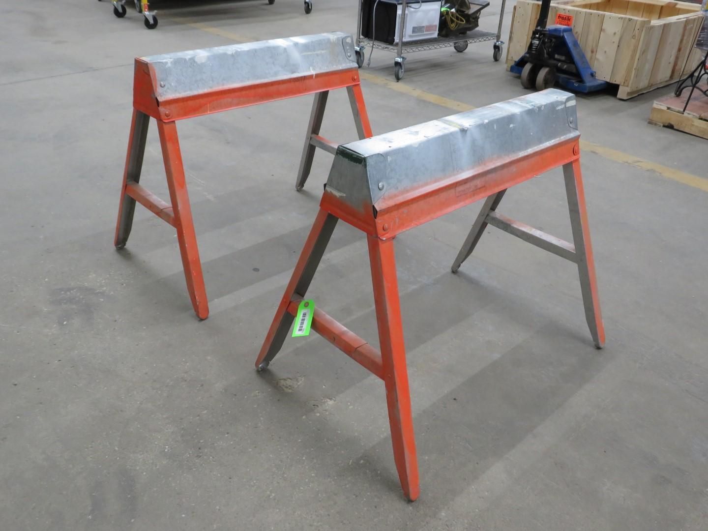 Two orange sawhorse-style sawhorses with metal tops on a concrete floor.