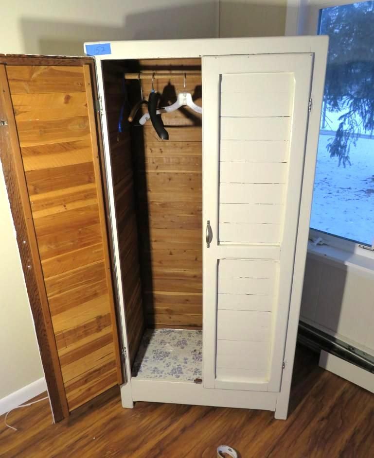 White armoire with open door, showing clothing rod and cedar interior. Exterior painted white with shuttered door, indoors.