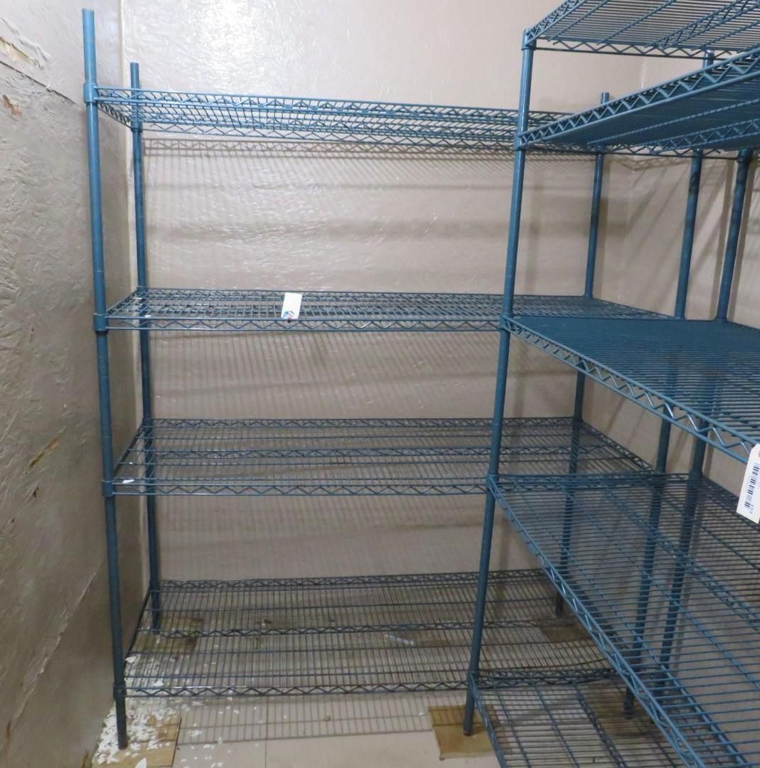 Blue wire shelving units in a corner, against beige walls.