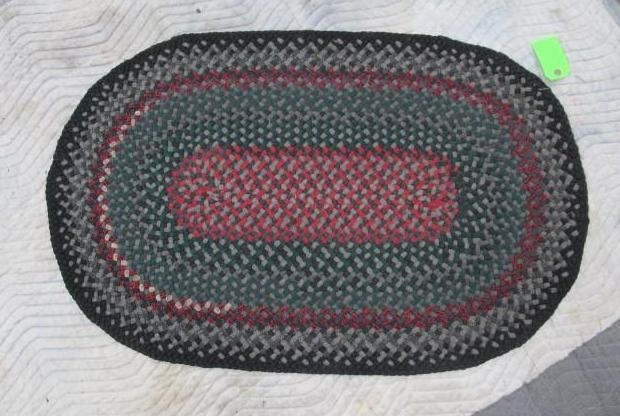 Oval braided rug with red, green, and black colors.