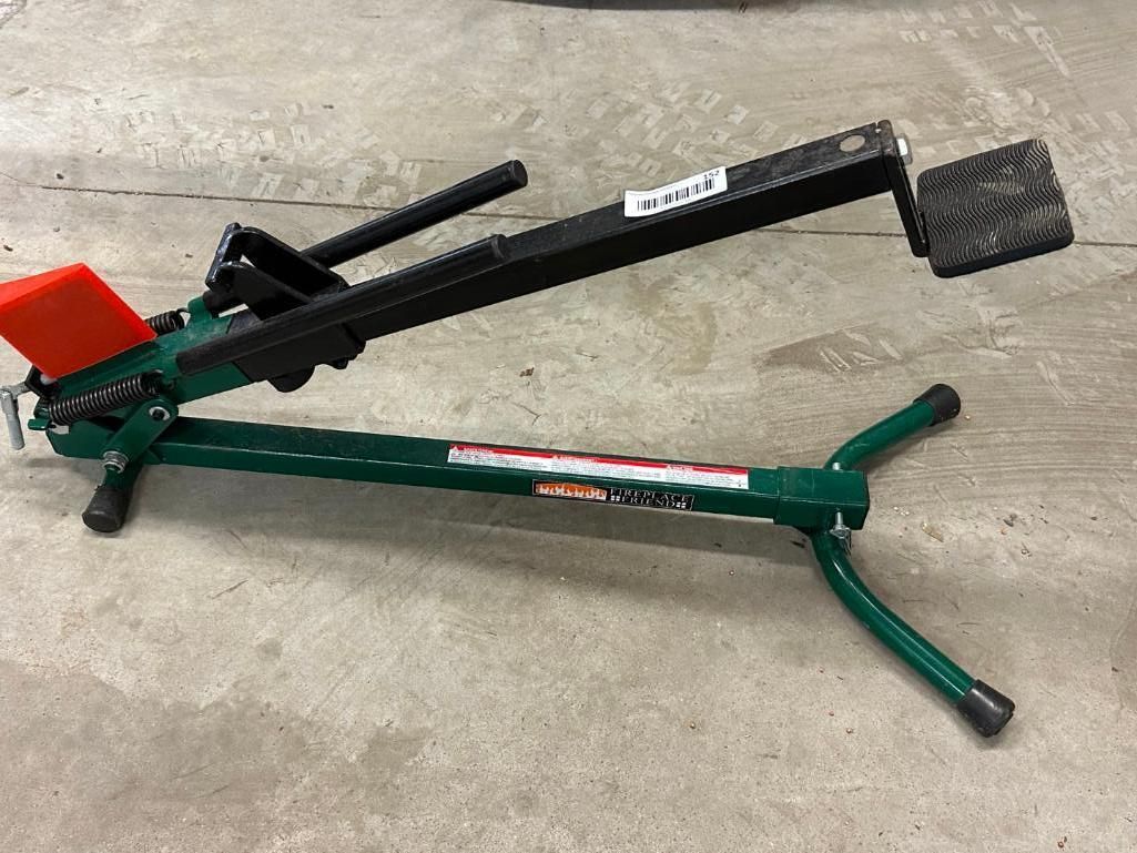 Green and black gun rest on a concrete floor with an orange lever.