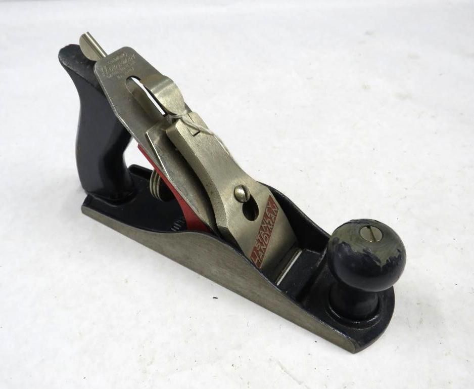 Hand plane on a white surface, black and silver with a wooden handle.