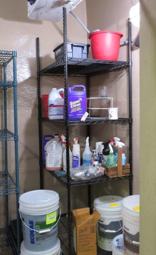 Black wire shelving unit holding cleaning supplies and buckets in a storage area.