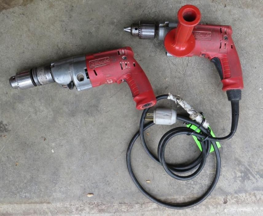 Two red and silver electric drills on a concrete surface.
