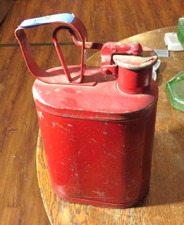 Red vintage metal gas can with a blue handle on a wooden table.