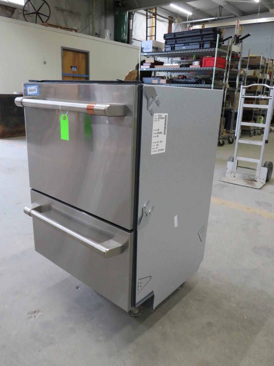 Stainless steel commercial dishwasher with two drawers in a warehouse setting.