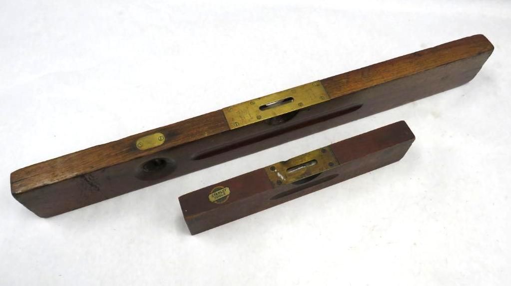 Two antique wooden spirit levels with brass accents, against a white background.