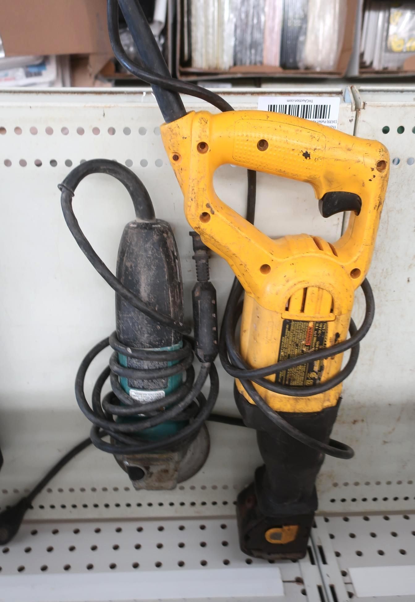 Yellow and black power tools hanging on a shelf: angle grinder and hammer drill.
