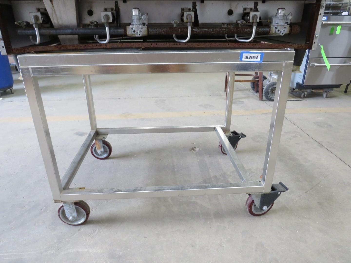 Stainless steel cart with wheels, supporting a kitchen appliance with burners.