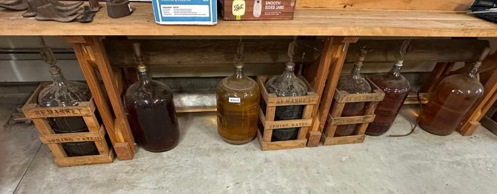 Bottles of liquid in wooden crates under a wooden shelf.