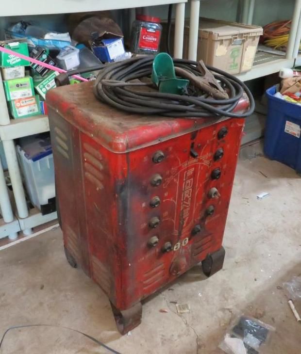 Red Lincoln arc welder with black cables and clamp.