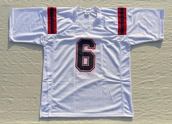 White sports jersey with number 6, red and navy details on shoulders and neckline.