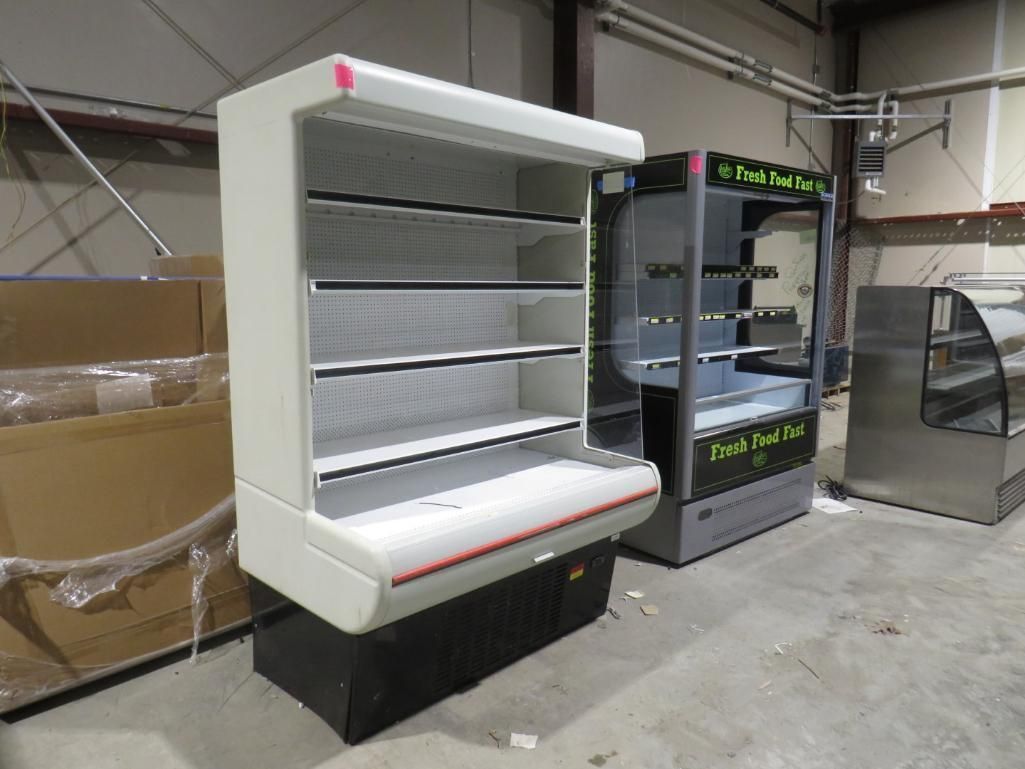 Three commercial refrigerated display cases, empty shelves, in a warehouse setting.
