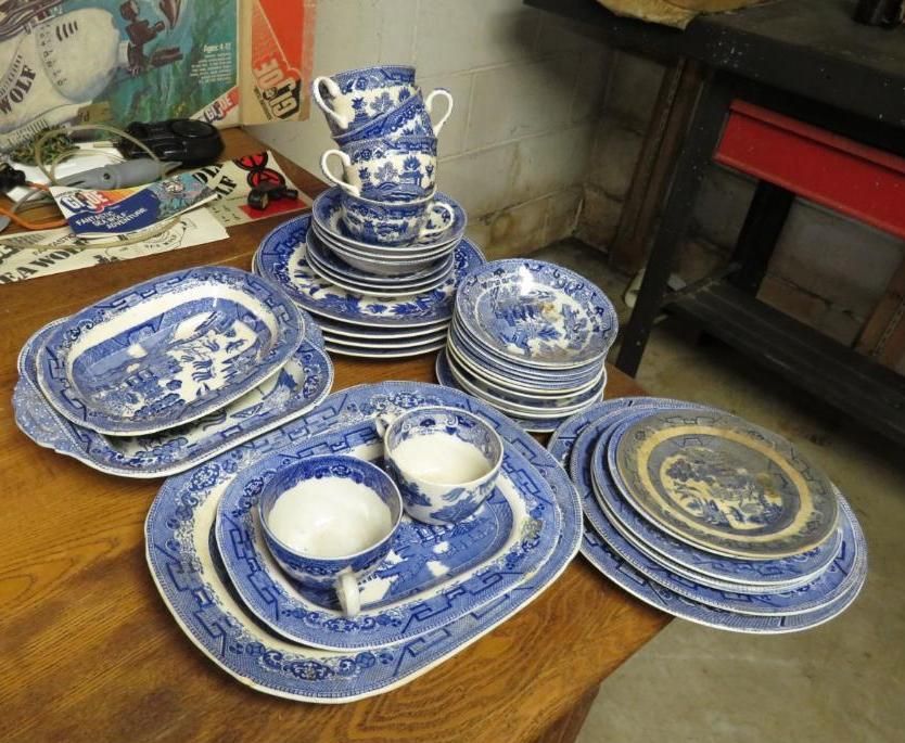 Blue and white ceramic dishes on a wooden table. The set includes plates, cups, and serving platters.