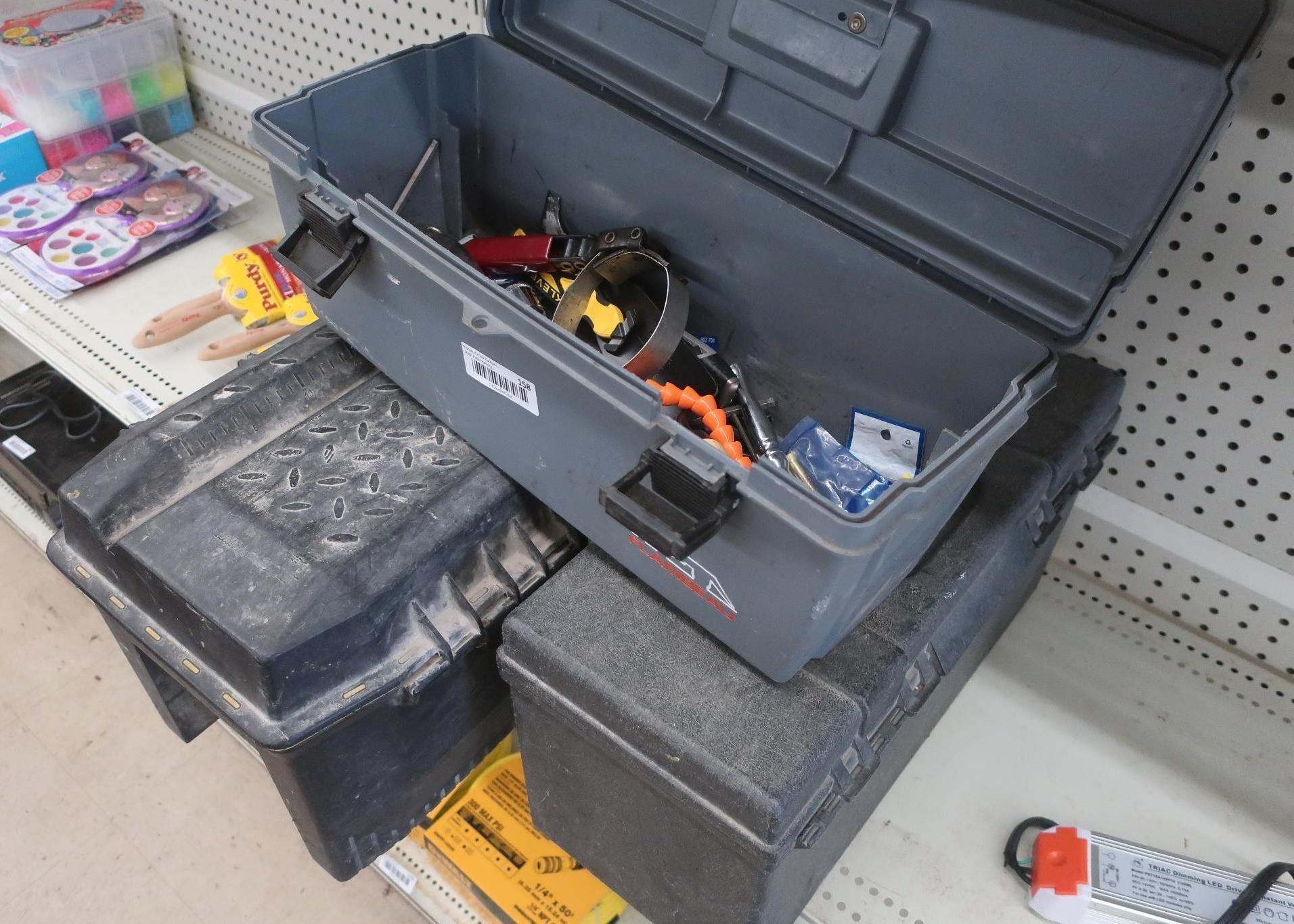 Gray tool box, open, atop two black tool boxes on a shelf.
