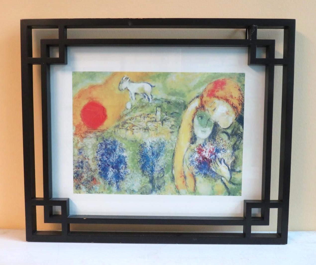 A framed print of a colorful Chagall-style painting, featuring figures, a sun, and a white horse.