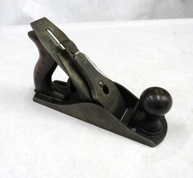 Hand plane on a white surface, dark wood handle, gray body, blade visible.