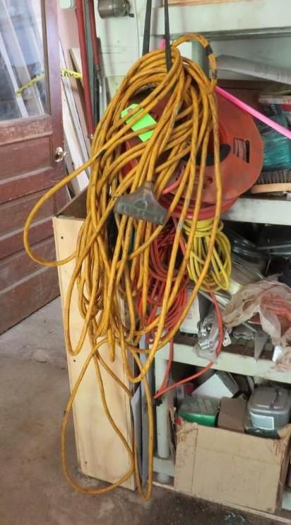 Yellow extension cord with a gray plug hanging in a workshop.
