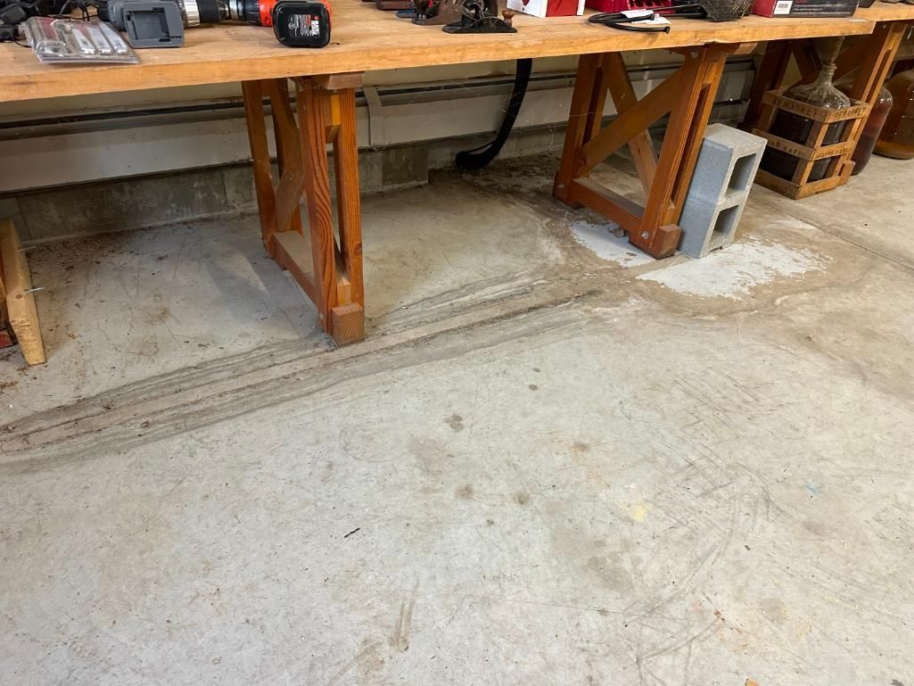 Workbench with tools above, concrete floor with tire tracks and debris.