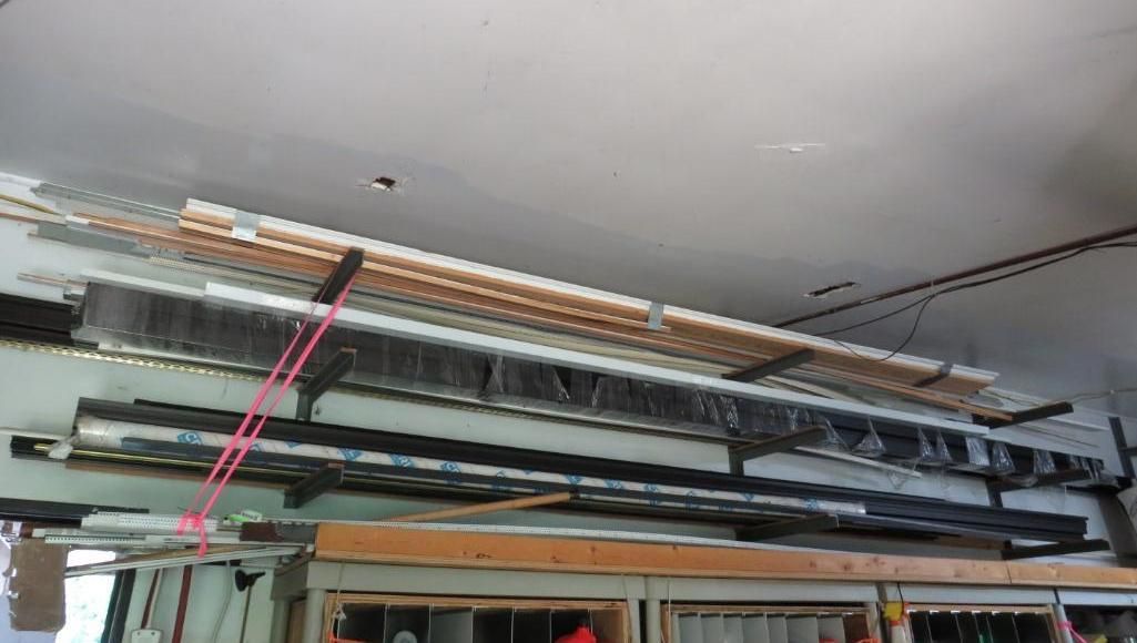Lumber and metal beams stored on shelves attached to a ceiling.