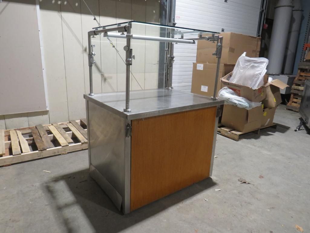Stainless steel and wood display stand with overhead frame in a warehouse.