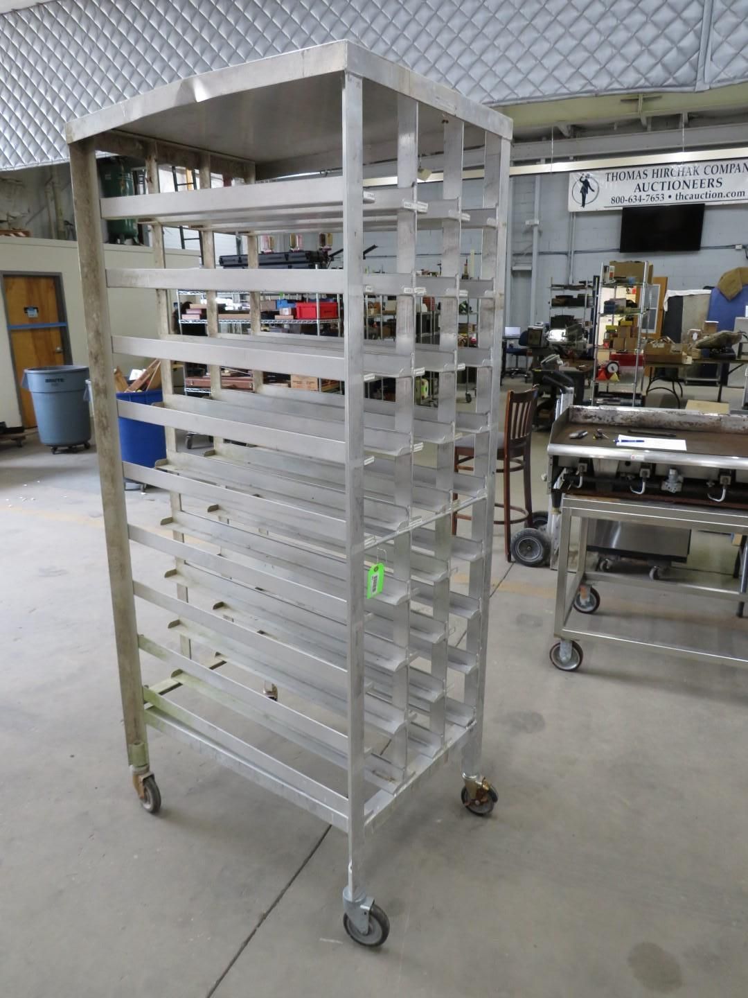 Stainless steel rack on wheels in a workshop setting, likely for food service.