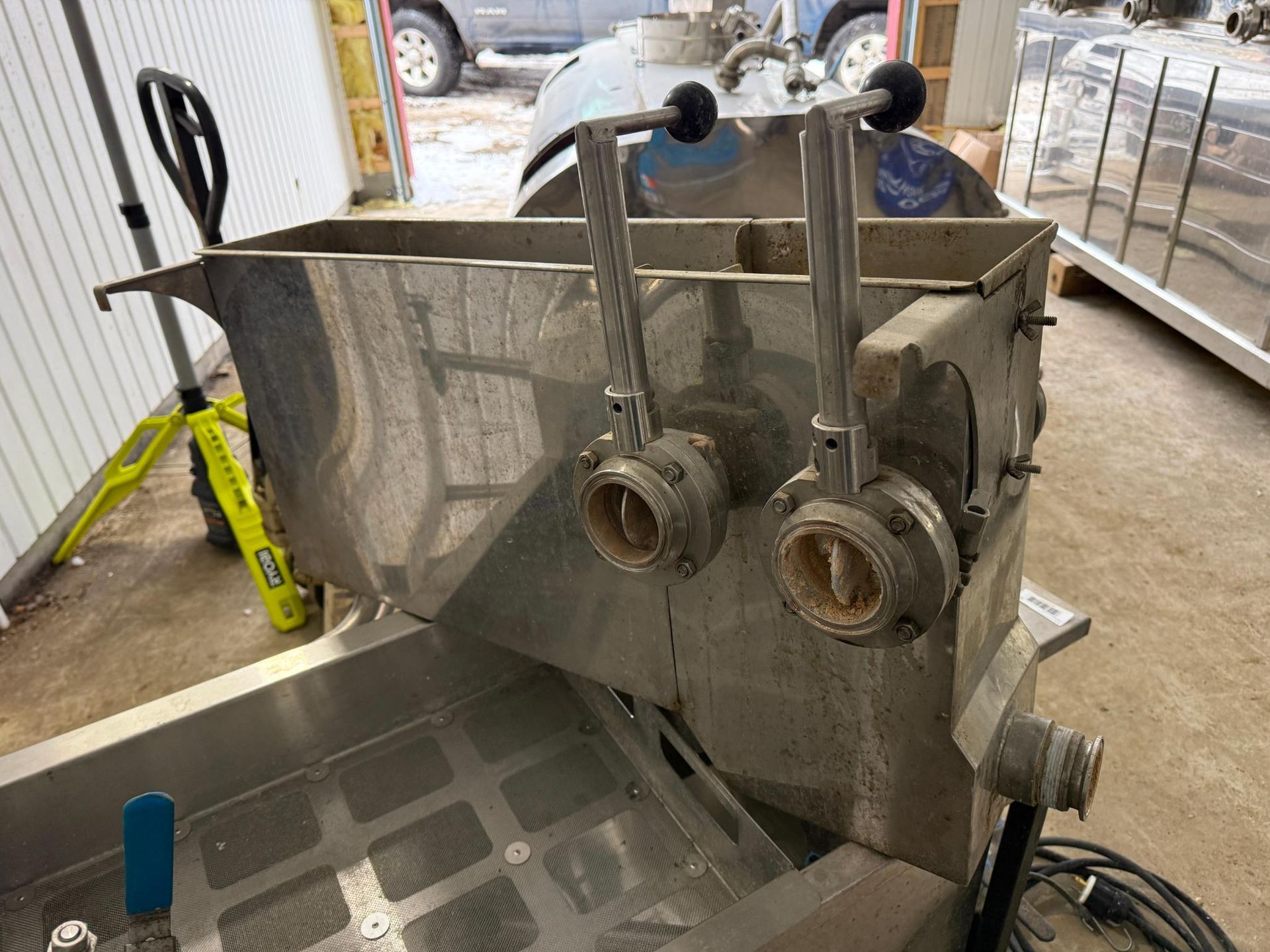 Stainless steel industrial mixing machine with levers and valves.