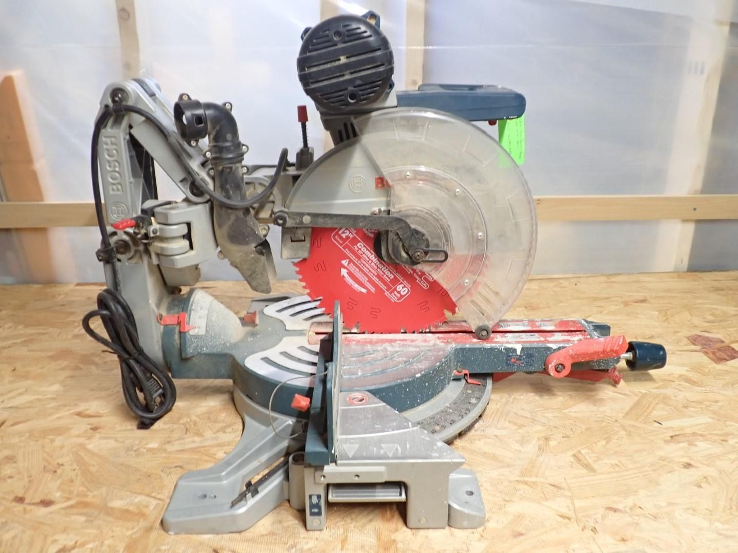 A gray and red miter saw on a wooden surface, ready to cut.