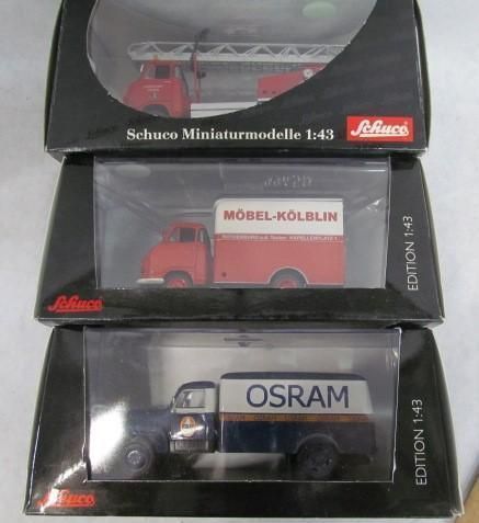 Three toy trucks in boxes: a fire truck, a moving truck, and an Osram truck.
