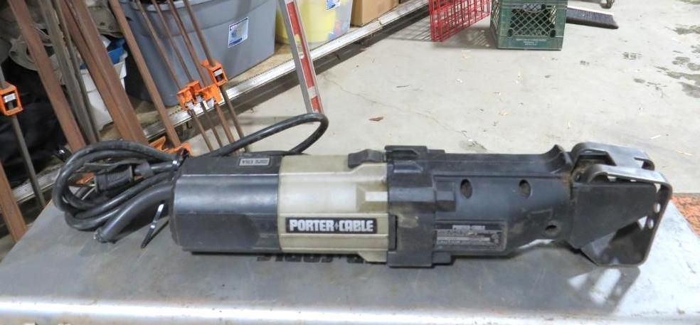 Porter-Cable reciprocating saw on a gray surface with tools and other items in the background.