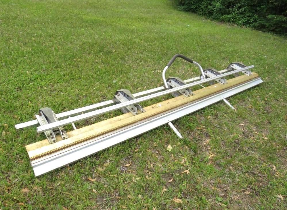 Metal gutter bender on green grass. Silver and wooden components with black handle.