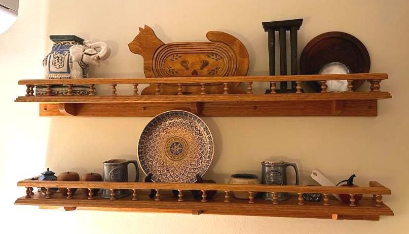 Two wooden shelves with decorative objects, including pottery and carved items, against a beige wall.