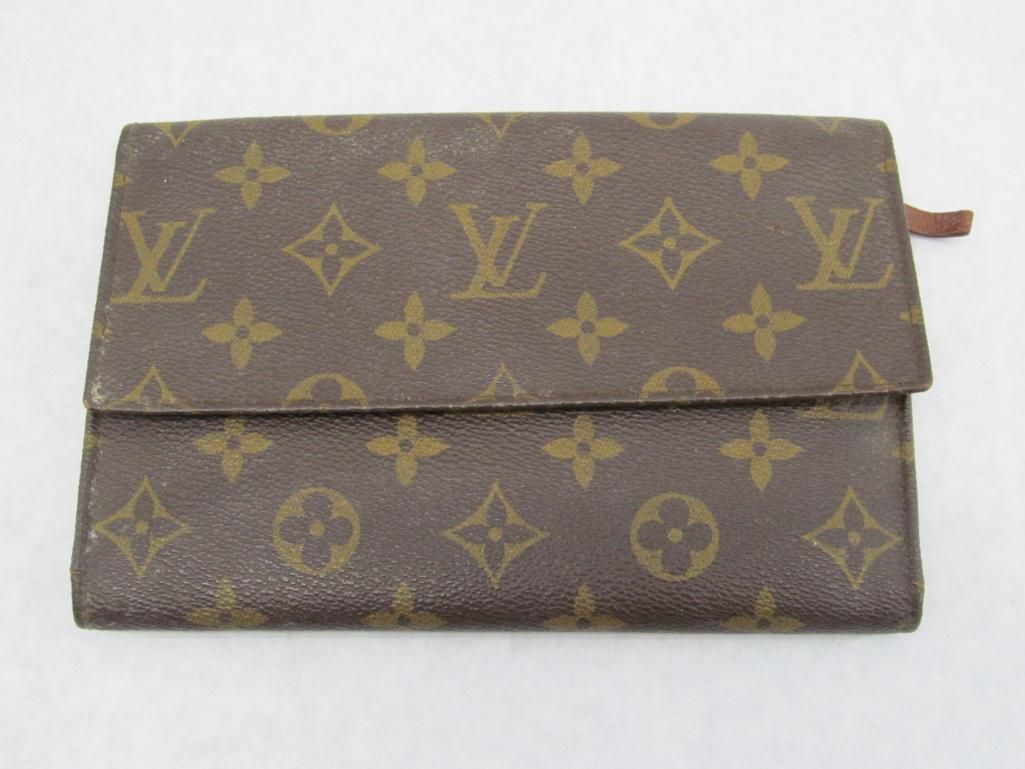 Brown Louis Vuitton wallet with monogram pattern, folded, on white.