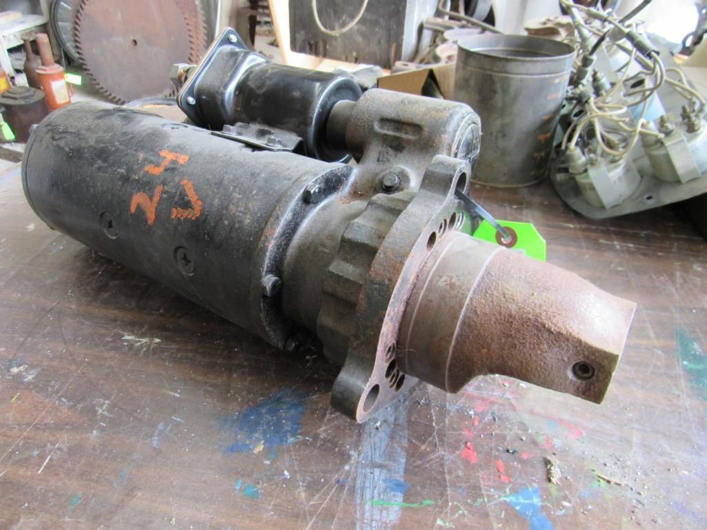 Black starter motor with nose, on a workbench.