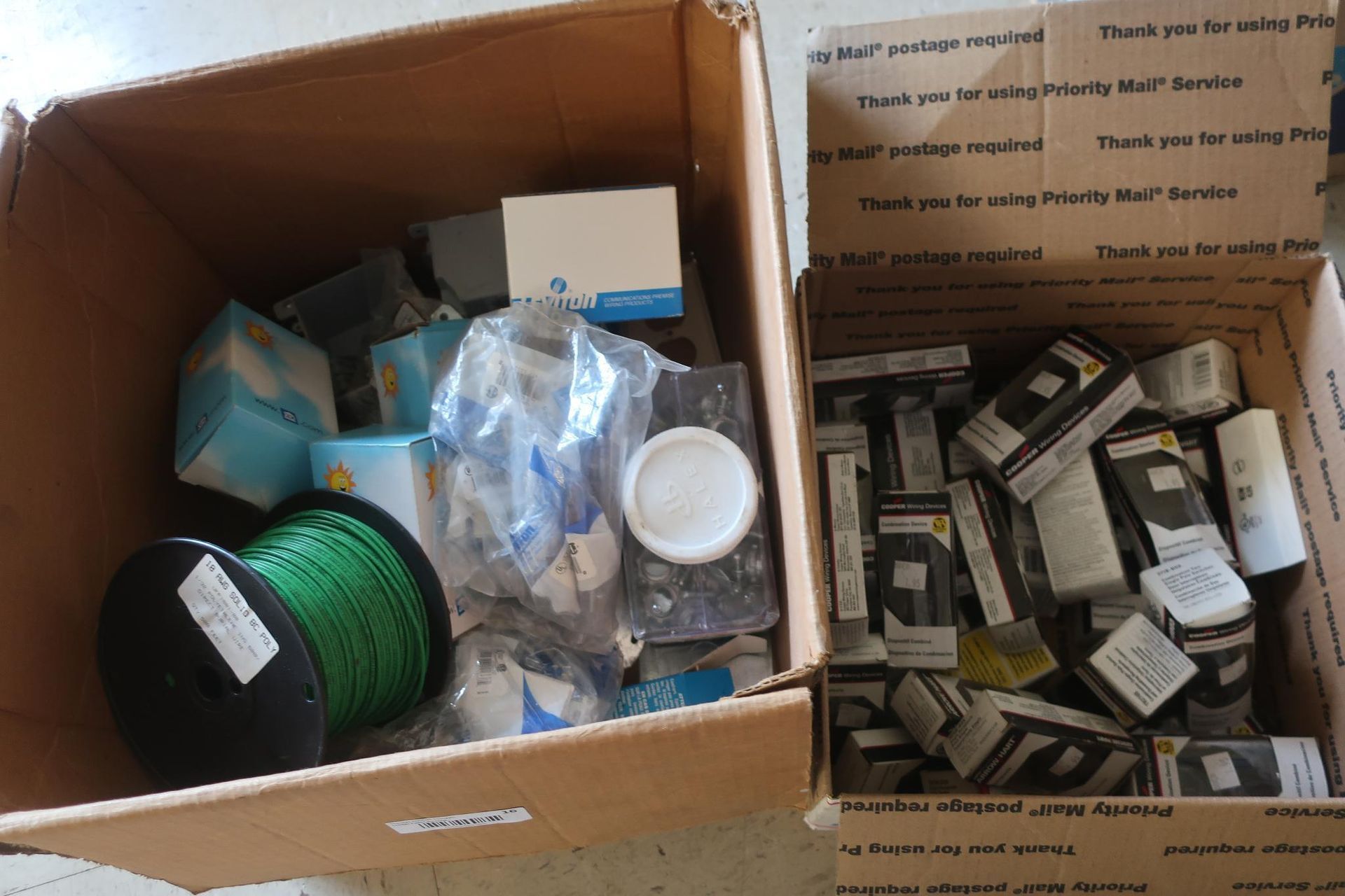 Two open cardboard boxes filled with various electronic components and supplies.