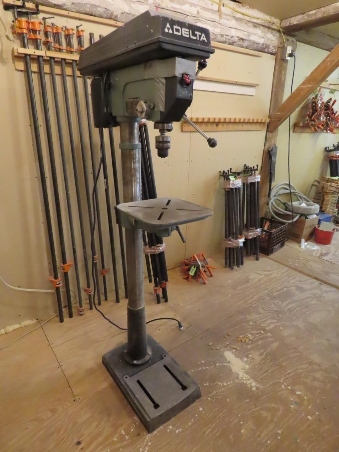 Delta drill press in a workshop, black and gray, standing on a heavy base