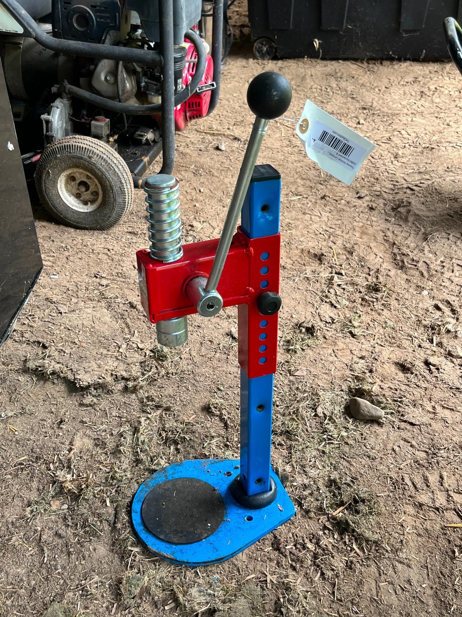 Red and blue bottle capper with a black handle, sitting on a blue base.