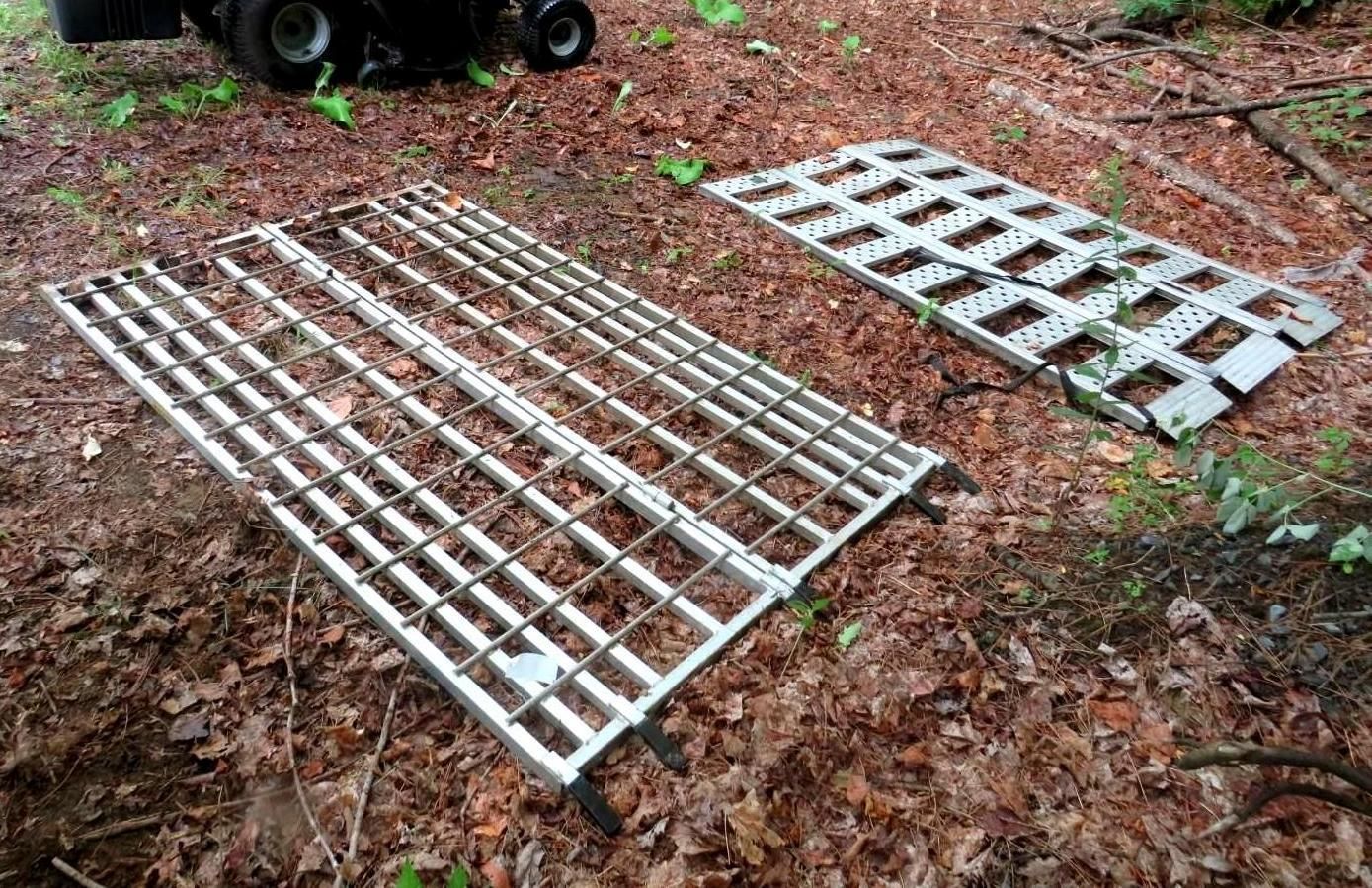 Two silver metal trackways on brown leaves, possibly for vehicle access, in a wooded area.