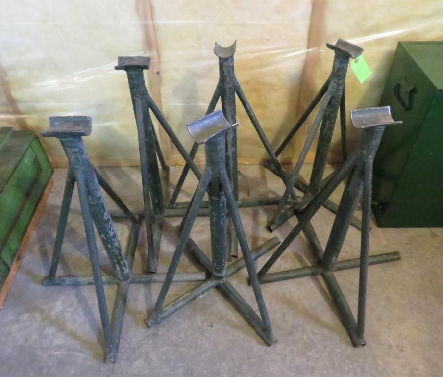 Six metal jack stands on a light-colored wooden floor.