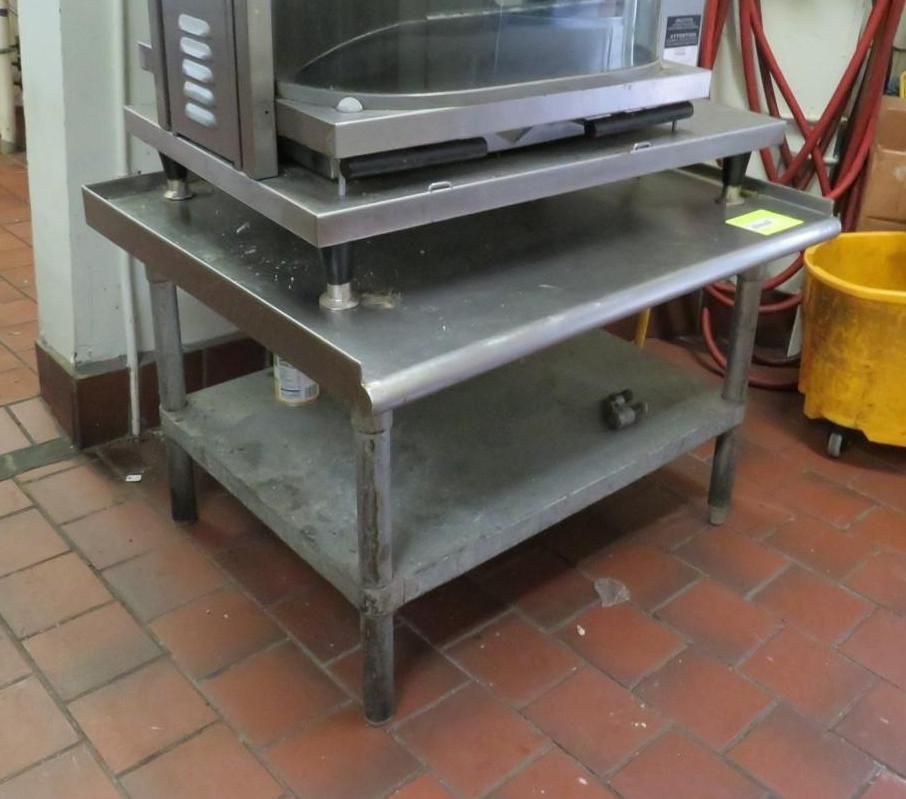 Stainless steel prep table with oven on top in a commercial kitchen.