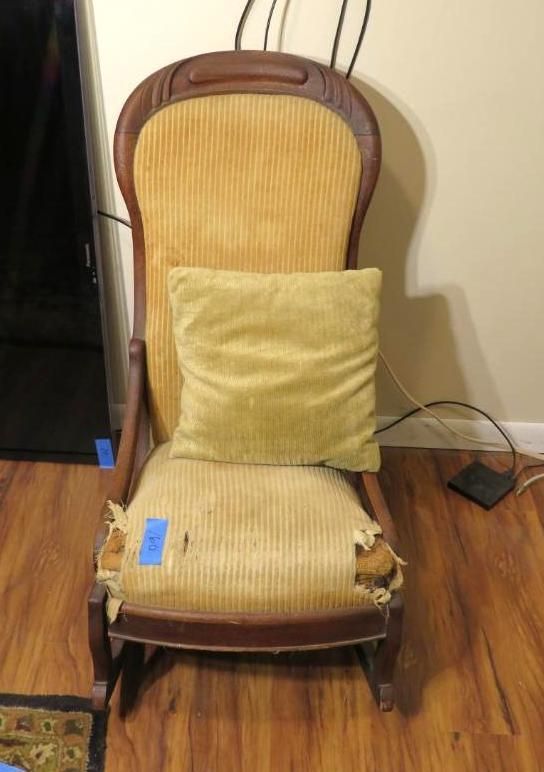 A wooden rocking chair with yellow upholstery and a matching pillow on a wooden floor.