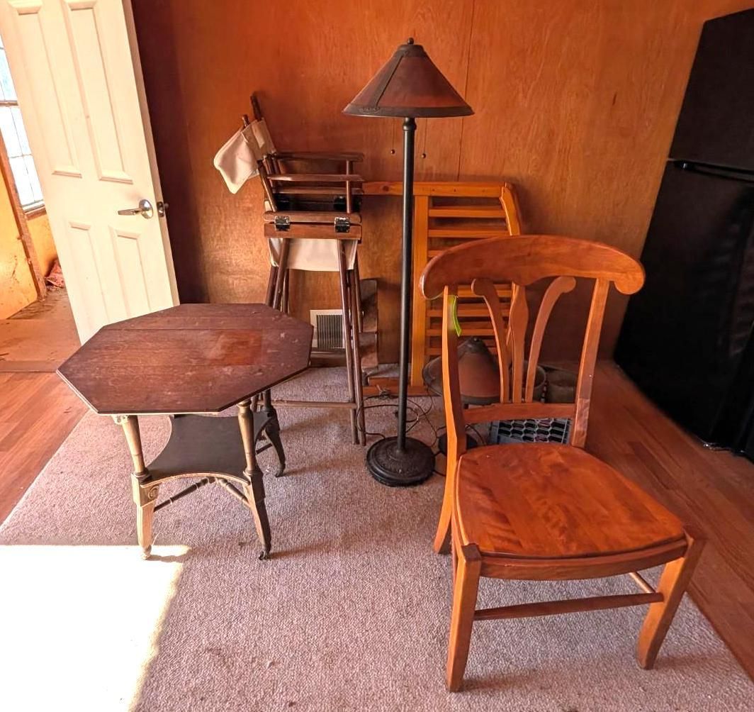 Assorted wooden chairs, small table, and floor lamp in a carpeted room with wood-paneled walls